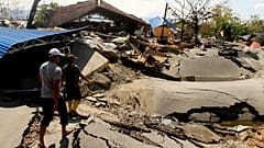People walk in an area hit by an earthquake in Palu, Indonesia