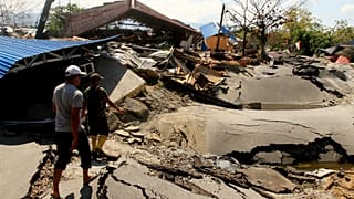 People walk in an area hit by an earthquake in Palu, Indonesia