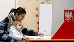 Mãe e filho numa mesa de voto das autárquicas polacas
