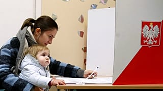 Mãe e filho numa mesa de voto das autárquicas polacas
