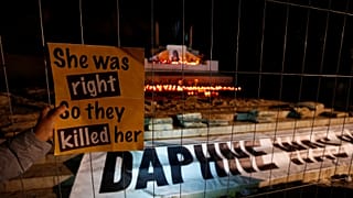 Plakat "She was right, so they killed her" vor Kerzen