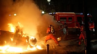 Firemen extinguish burning cars set alight by protesters