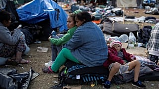 Migrantes esperan a ser trasladados a un nuevo refugio en Tijuana.