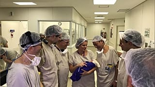 Medical team hold the first baby born via uterus transplant
