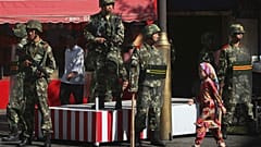 Doğu Türkistan'ın Urumçi kentinde, Çinli askerlerin önünden geçen Uygur kız