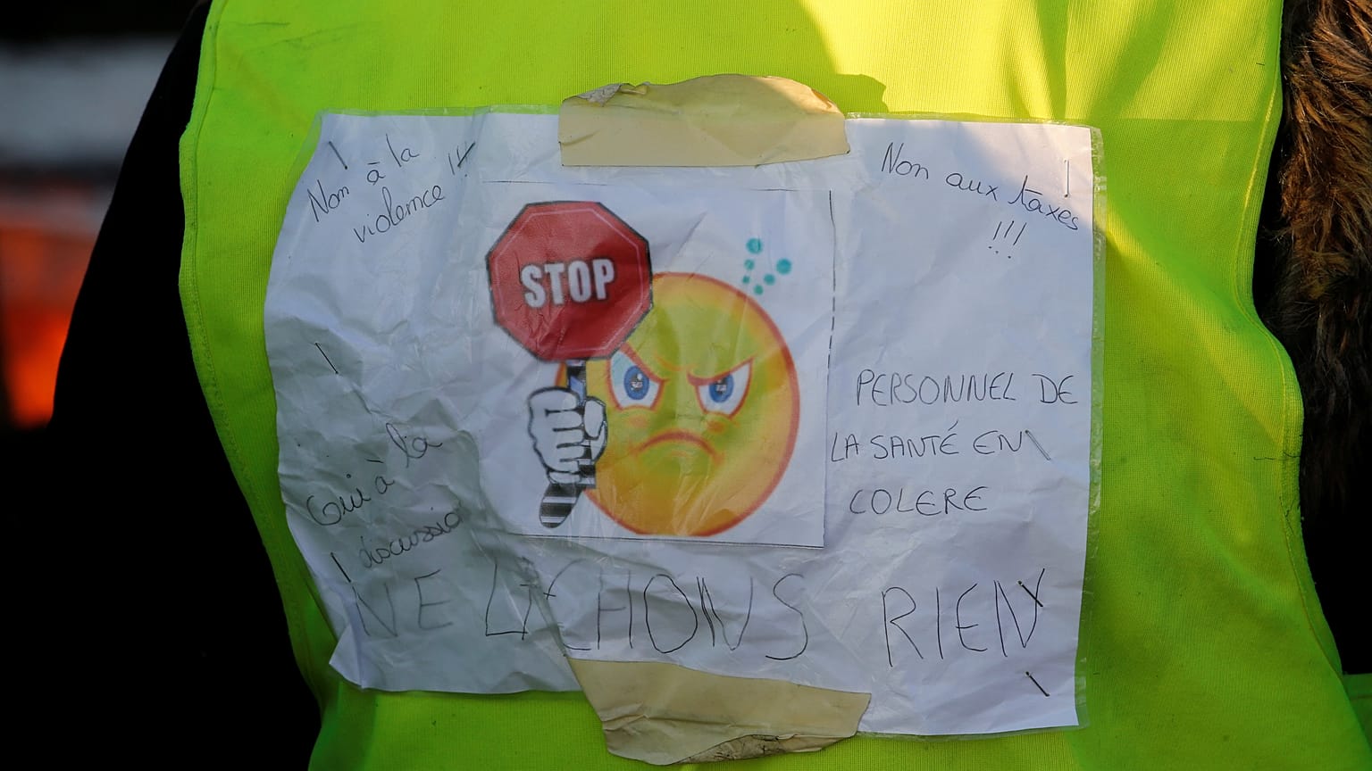 A protester wears a yellow vest bearing the slogan "don't give up."