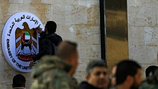 A man works on the emblem of the UAE embassy in Damascus