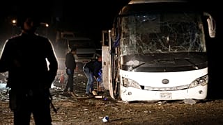 Police officers inspect a scene of a bus blast in Giza