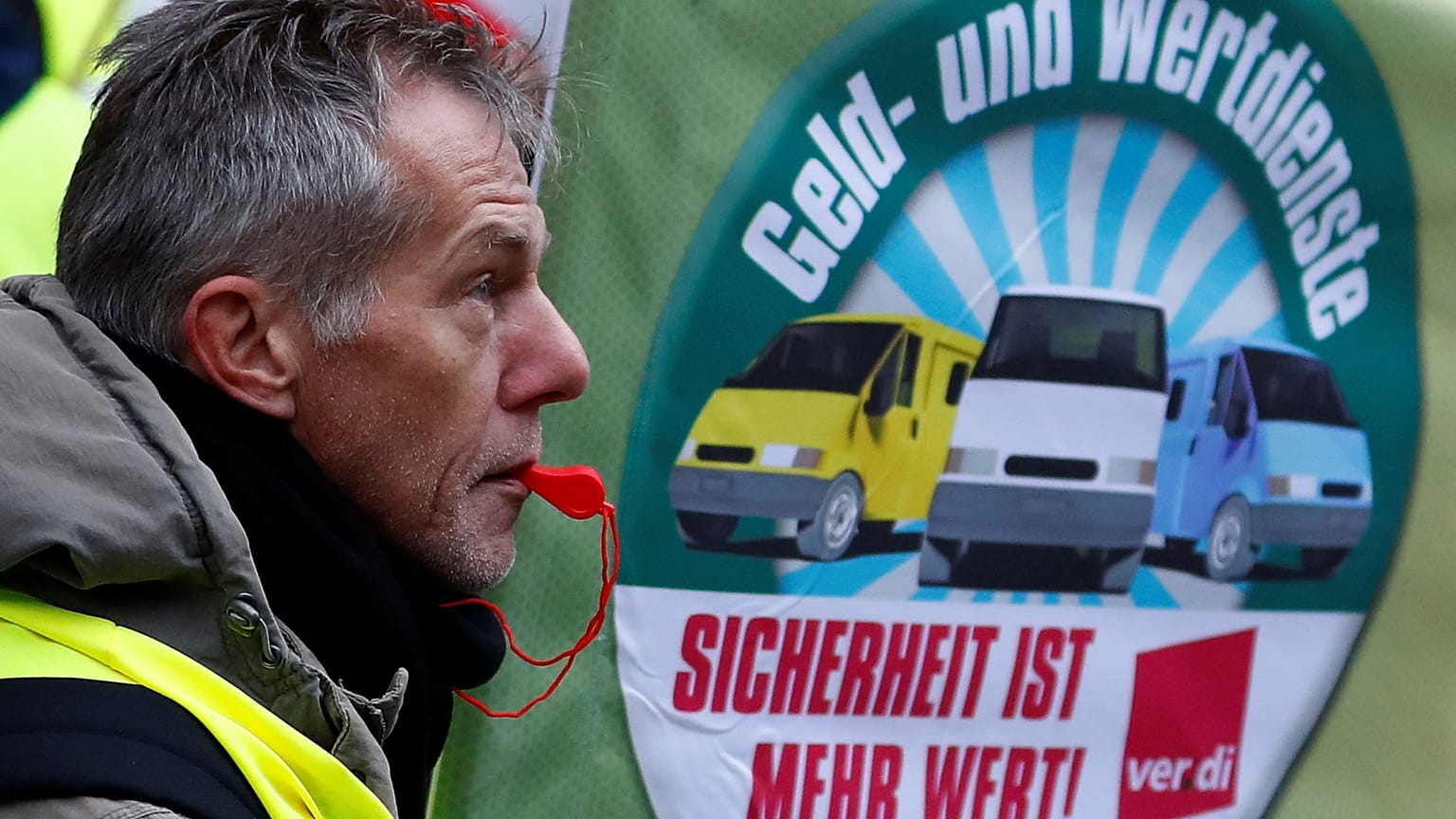 Ein Streikender mit Trillerpfeife vor einem ver.di-Banner