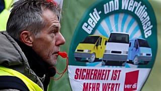 Ein Streikender mit Trillerpfeife vor einem ver.di-Banner