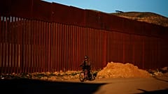 A man cycles along the US border in Tijuana, Mexico.