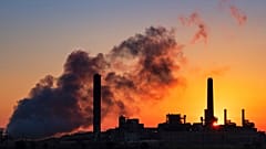 The sun rises behind a coal-fired power plant
