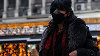 A woman covers her face as air pollution reaches dangerous levels in Skopje