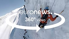 A man is pick climbing an ice hill