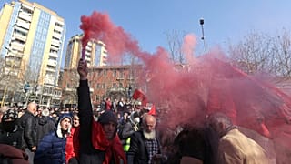 A protester holds a flare during an anti-government rally in Albania