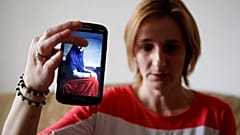 سيدة بوسنية تحمل هاتف محمول عليه صورة أختها في سوريا