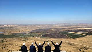عدد من دروز الجولان المحتل يجلسون مقابل الشطر الشمالي داخل سوريا