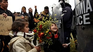 کودکان پناهجویان به پلیس ضدشورش گل هدیه می‌کنند- یونان- اردوگاه دیاواتا
