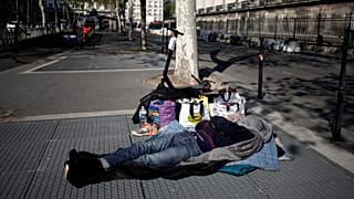 Paris'te bir evsiz metro havalandırmasının üzerinde uyuyor