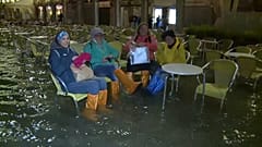 À mesa de uma esplanada com galochas e água pelos tornozelos
