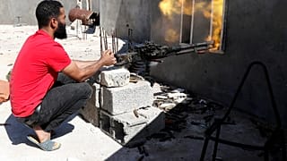 A fighter fires a heavy machine gun during clashes with Haftar's forces