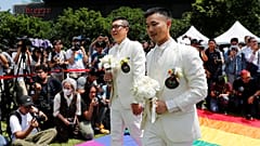 Gay newlyweds walk on a giant rainbow flag in Taipei on May 24, 2019.