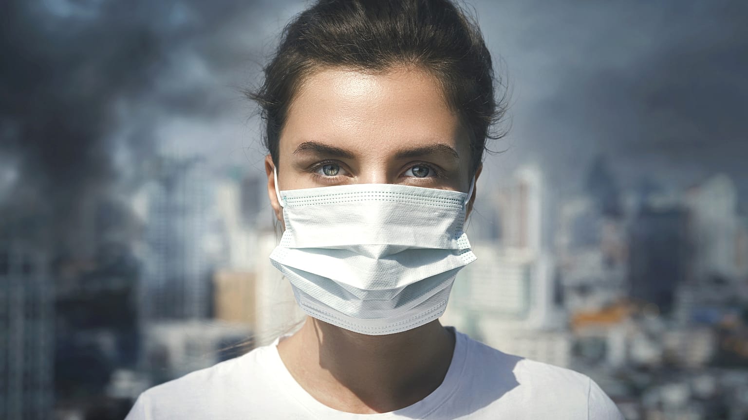 Air pollution in the city. Woman wearing face mask for protection.