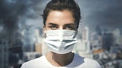 Air pollution in the city. Woman wearing face mask for protection.