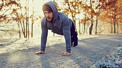 Young runner doing push ups exercise during cold autumn morning