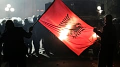 Anti-government supporters hold an Albanian flag in front of police during a protest in Tirana