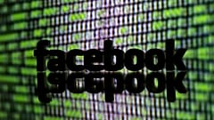 A 3D-printed Facebook logo is seen in front of a displayed cyber code