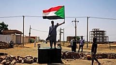 متظاهر يرفع علم السودان