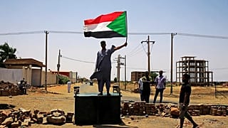 متظاهر يرفع علم السودان