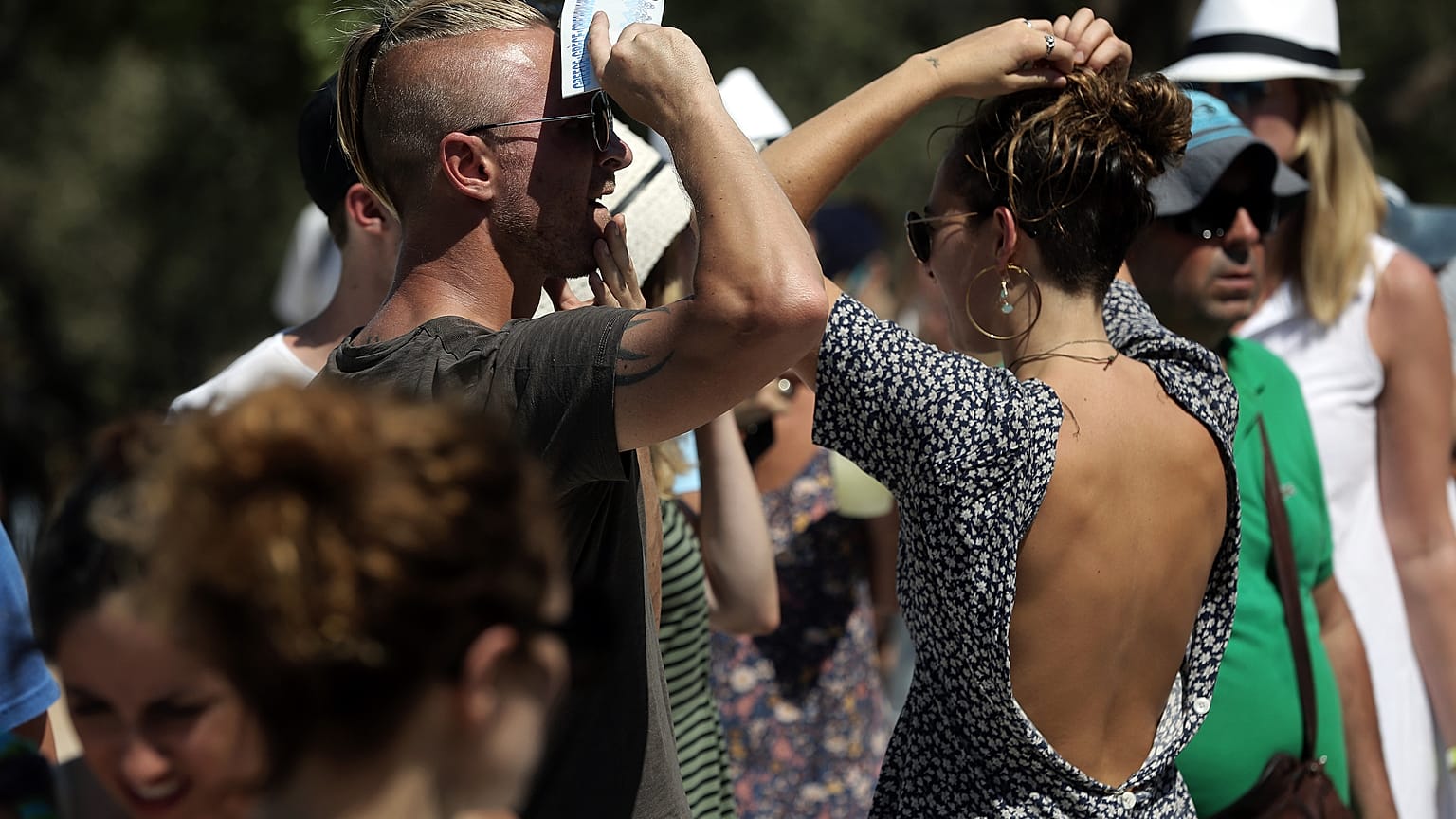 Τουρίστες προσπαθούν να προστατευθούν από το δυνατό ήλιο της Αθήνας