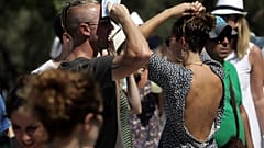 Τουρίστες προσπαθούν να προστατευθούν από το δυνατό ήλιο της Αθήνας