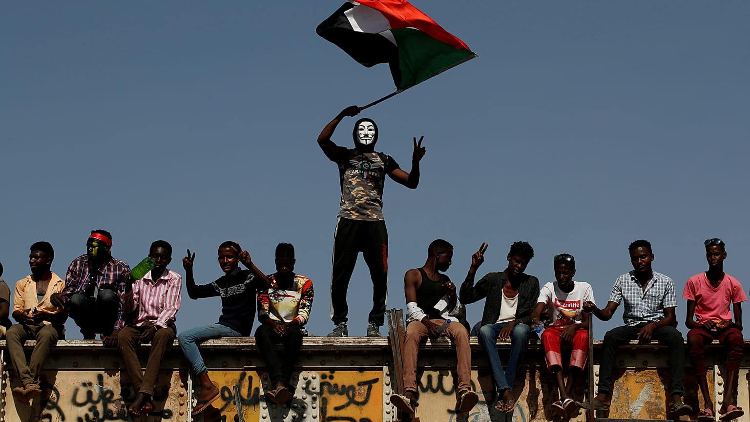 FILE PHOTO: A Sudanese protester wearing a Guy Fawkes mask waves a national flag outside the Defense Ministry compound in Khartoum