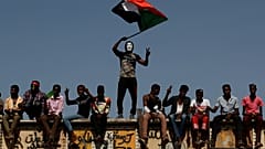 FILE PHOTO: A Sudanese protester wearing a Guy Fawkes mask waves a national flag outside the Defense Ministry compound in Khartoum