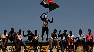 FILE PHOTO: A Sudanese protester wearing a Guy Fawkes mask waves a national flag outside the Defense Ministry compound in Khartoum