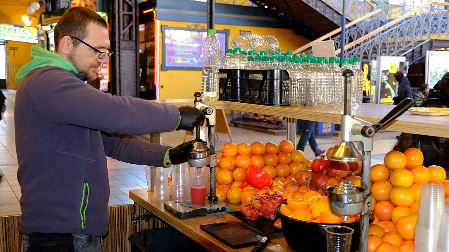 Narancsból, grapefruitból és gránátalmából préselt üdítőitalokat árul egy férfi a Fővám téri Vásárcsarnokban.