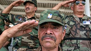 Veteranos militares hondureños saludan la bandera durante un servicio conmemorativo en honor a las víctimas de la'Guerra del Fútbol' de 1969.