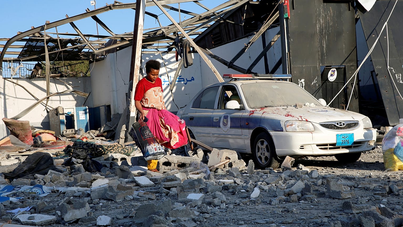A Tripoli melletti lebombázott menekülttáborban gyűjt ruhákat egy migráns