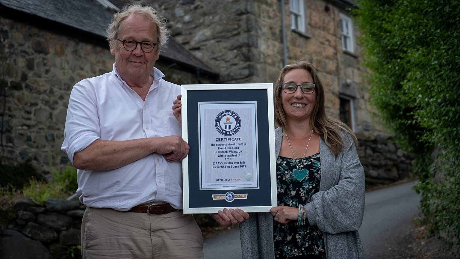 Gwyn Headley and Sarah Badham hold a certificate for the record title for world's steepest street, in Harlech, Wales, Britain July 10, 2019.
