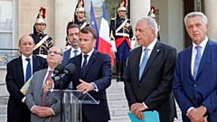 Frankreichs Präsident Macron neben Außenminister Le Drian und UN-Hochkommissar für Flüchtlinge Grandi