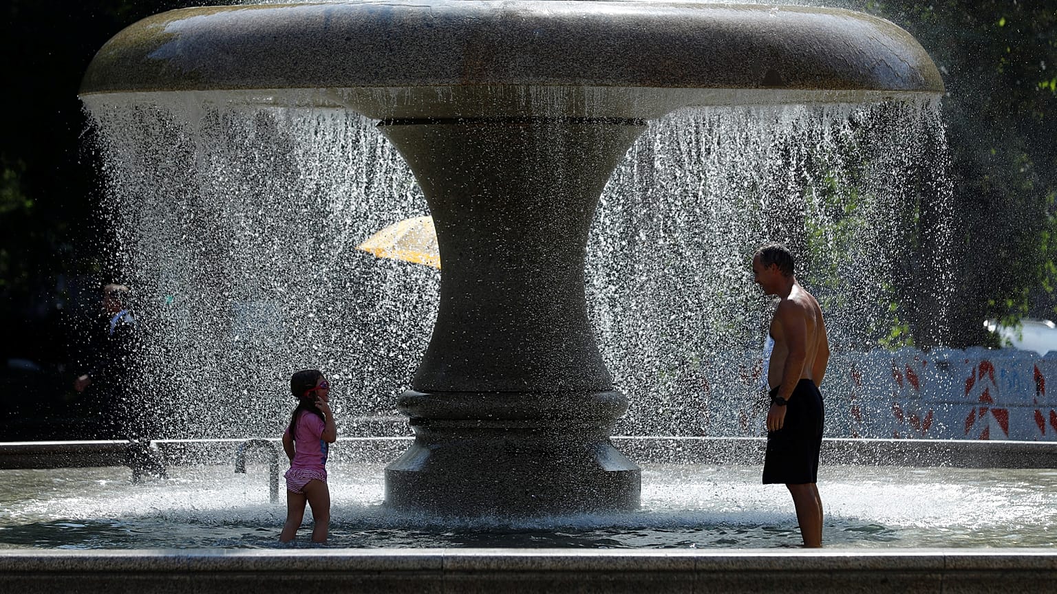 A man and a child cool off in a fountain on a hot summer day in Frankfurt