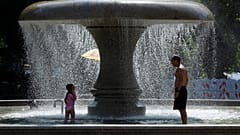 A man and a child cool off in a fountain on a hot summer day in Frankfurt