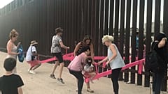 People play on a set of fluorescent pink seesaws across the US-Mexico border in Sunland Park, New Mexico, US