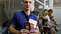 Un residente de la autoproclamada República Popular de Donetsk sostiene su pasaporte ruso y una copia de la Constitución de Rusia