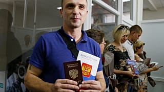 Un residente de la autoproclamada República Popular de Donetsk sostiene su pasaporte ruso y una copia de la Constitución de Rusia