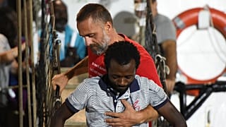 Un migrant aidé à descendre du navire humanitaire Open Arms