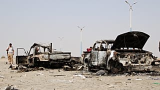 يمني من المقاتلين الانفصاليين يعاين حطام عربات قوات حكومية دمرها طيران الإمارات العربية خلال غارة قرب عدن